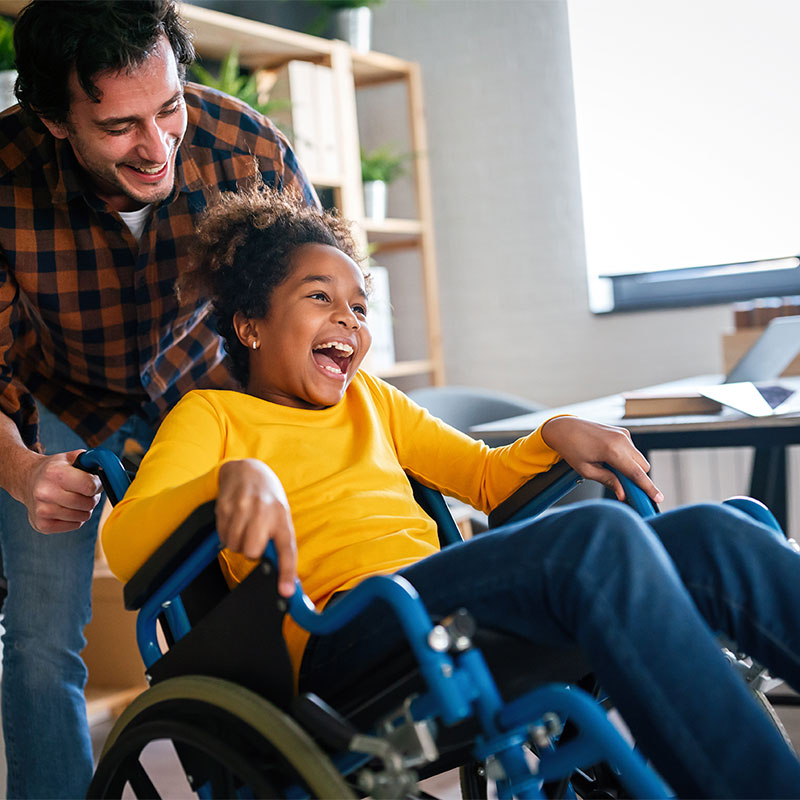 wheelchair-user A young girl in a wheelchair laughing with an aduly